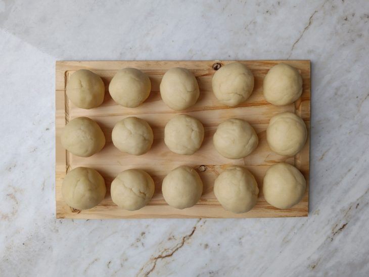 Porções de massa sobre uma tábua de madeira.