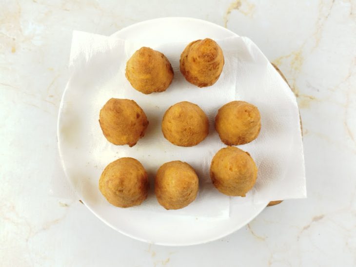 Coxinhas fritas e douradas, escorrendo no papel toalha.