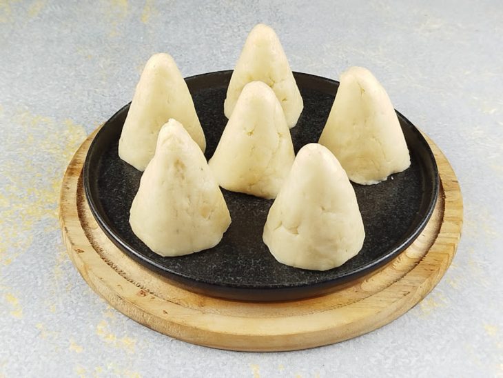 Massa recheada e modelada em formato de coxinha.