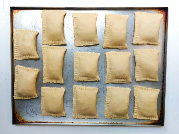 Pastéis fechado e dispostos em cima da assadeira.