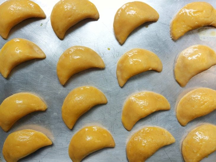 Uma forma contendo vários pastéis crus e pincelados com gema.