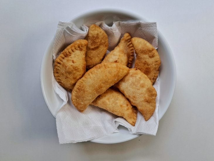 Pastéis fritos e acomodados em um recipiente com papel-toalha.