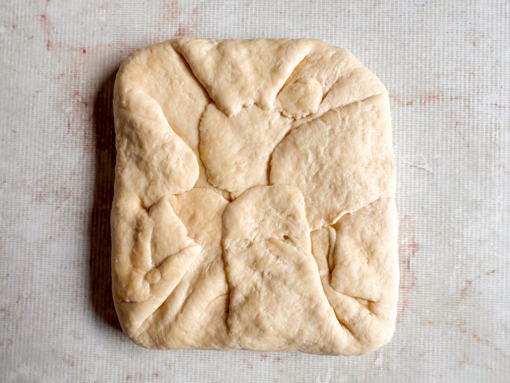 Bloco de manteiga dentro da massa, com as pontas dobradas sobre ele.