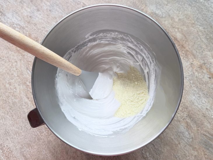 Leite em pó sendo misturado delicadamente ao merengue.