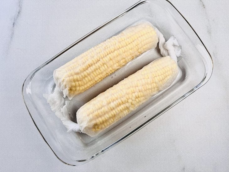 espigas de milho embaladas em papel toalha e molhadas para cozinhar no microondas.