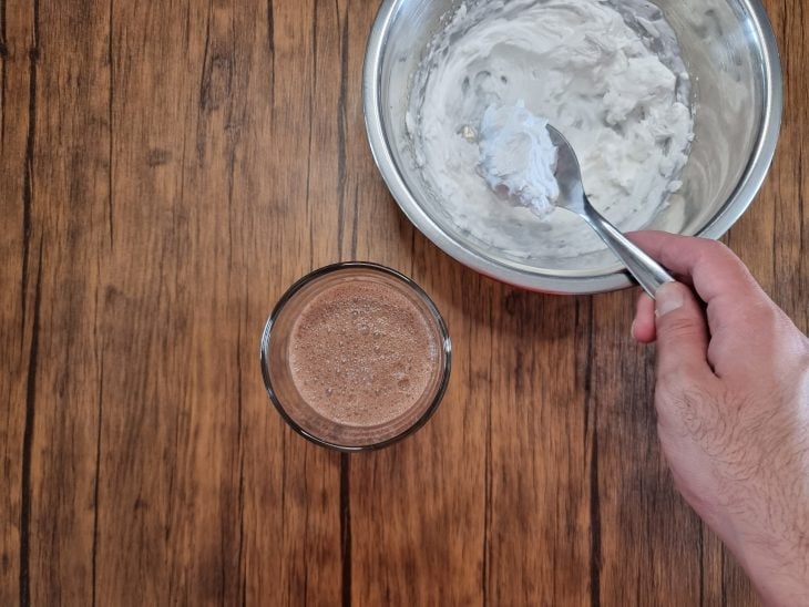 milkshake no copo, com uma colher de chantilly sendo colocada por cima