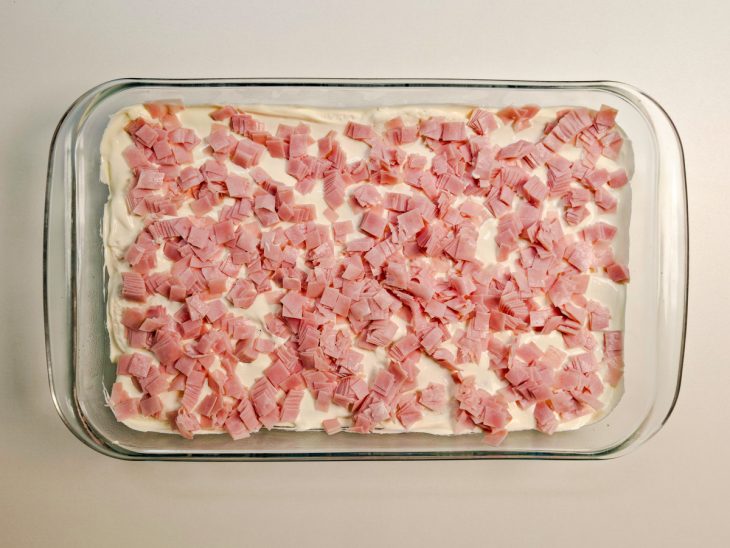 Presunto em tiras sendo distribuído por cima das bisnaguinhas.