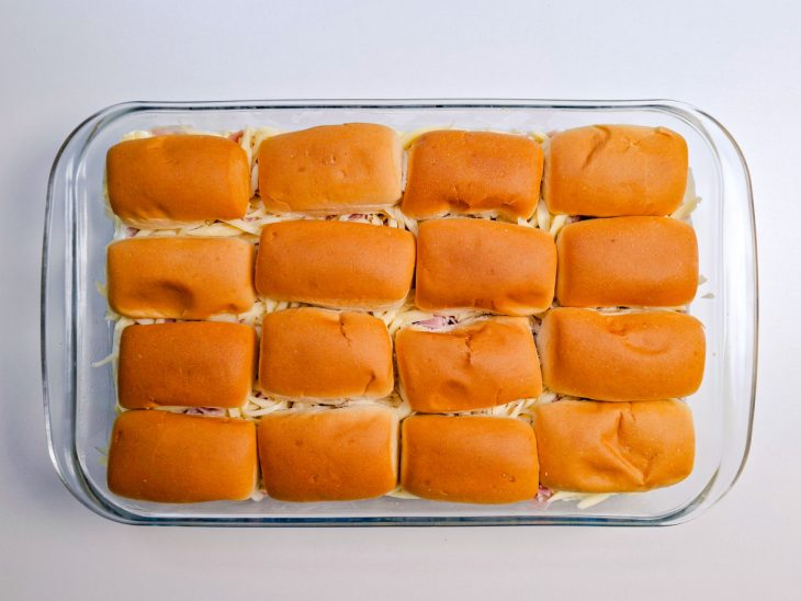 Tampas das bisnaguinhas sendo posicionadas sobre cada base.