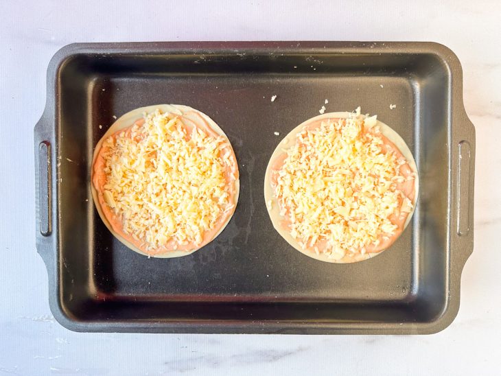 Na assadeira, o queijo ralado sobre as massas.