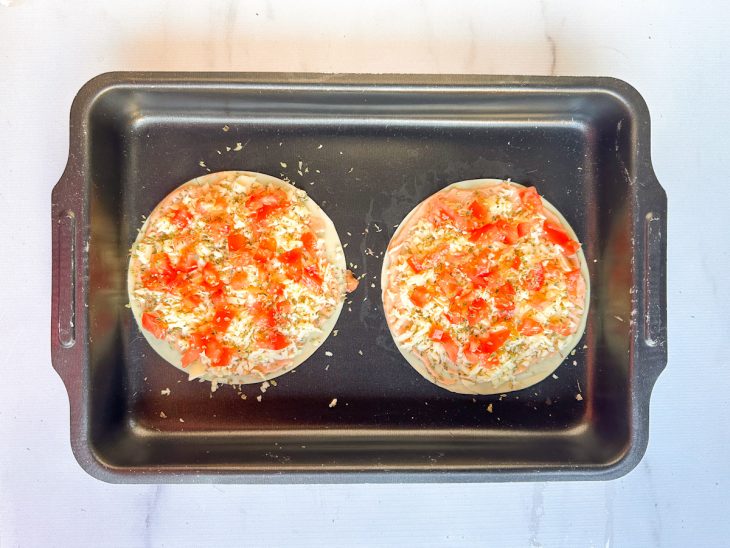 Na assadeira, os cubos de tomate, e o orégano adicionados ao recheio massa.