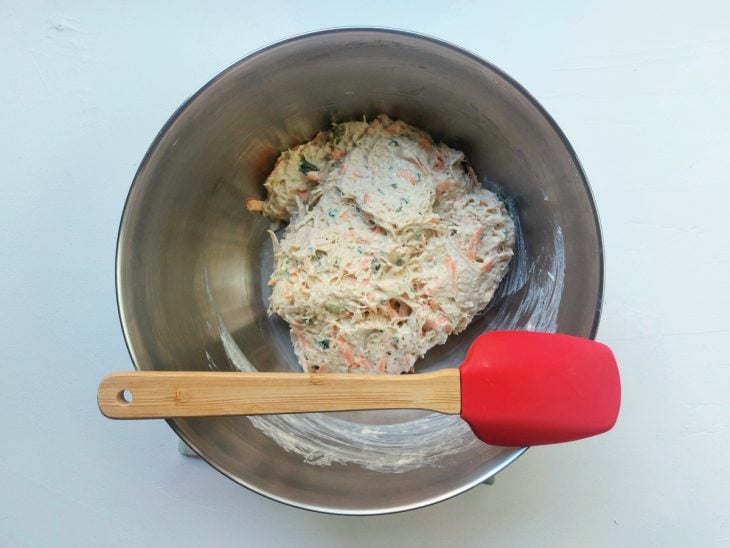 Um recipiente contendo a mistura de frango desfiado, cenoura ralada, azeitonas picadas, cheiro-verde, maionese e creme de leite.