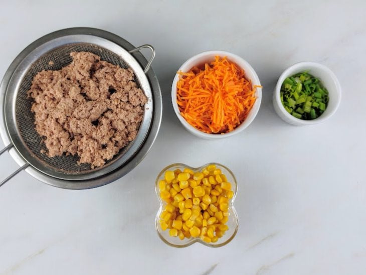 Ingredientes separados em recipientes e atum escorrido na peneira.