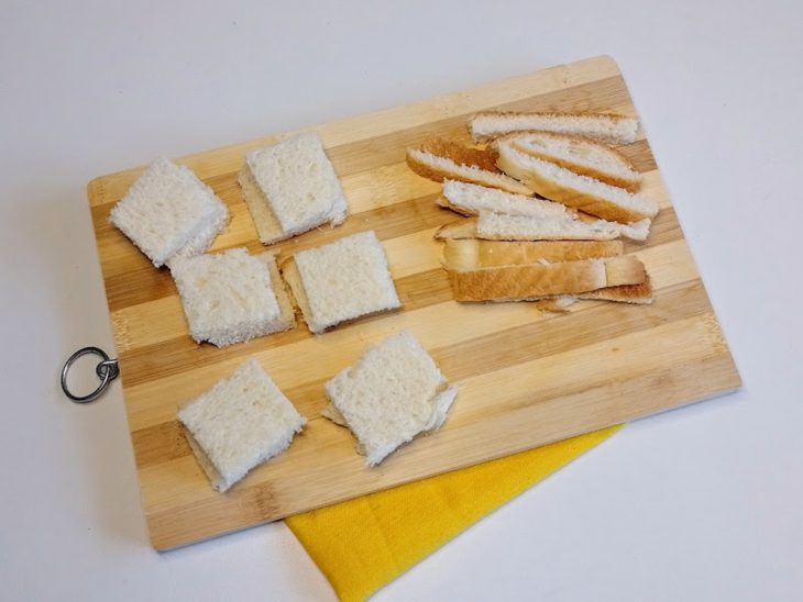 Uma tábua com fatias de pão cortadas e sem casca.