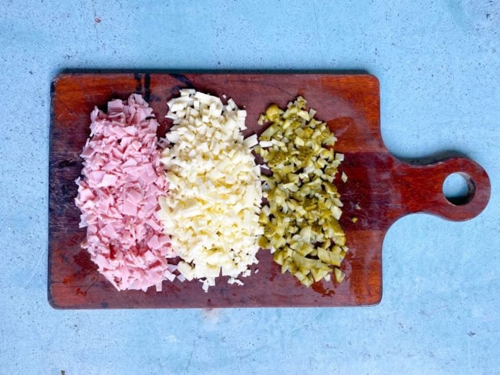 Uma tábua contendo presunto, queijo e pepino picados.