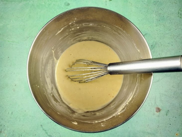 Uma tigela com farinha, leite, ovo, creme de cebola, óleo, açúcar, sal e fermento.