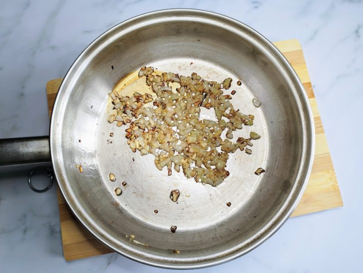 Uma frigideira com alho e cebola dourados.