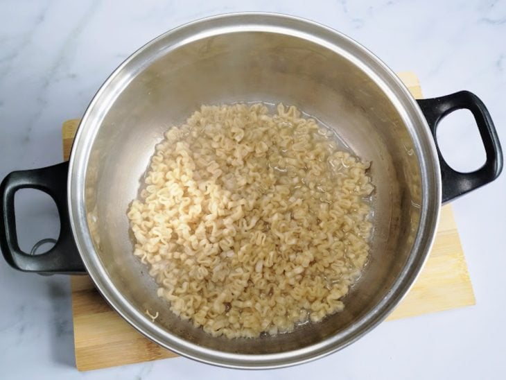 Uma panela com água e miojo.