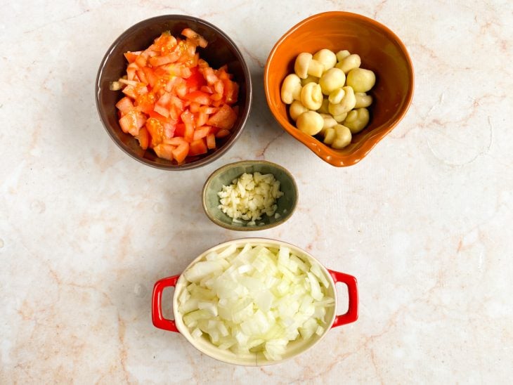 Recipientes com alho, cogumelos, tomate e cebola picadinhos.