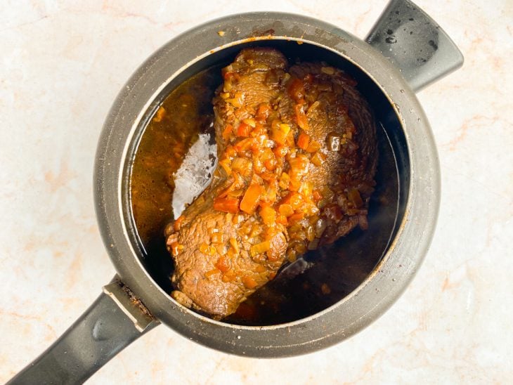 Panela com a carne, alho, tomate, cebola, shoyu, cerveja preta e temperos.