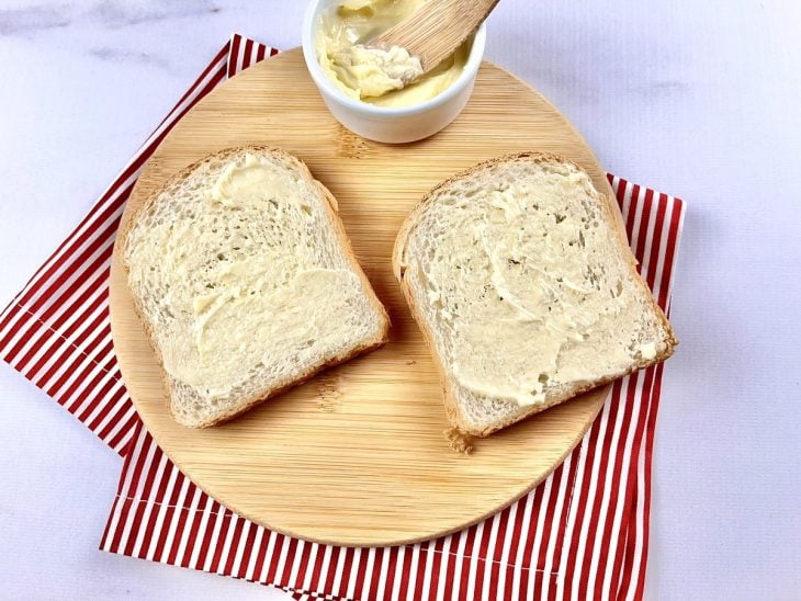 Uma tábua contendo duas fatias de pães com manteiga.