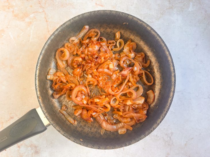 Cebolas douradas e caramelizadas dentro da panela.
