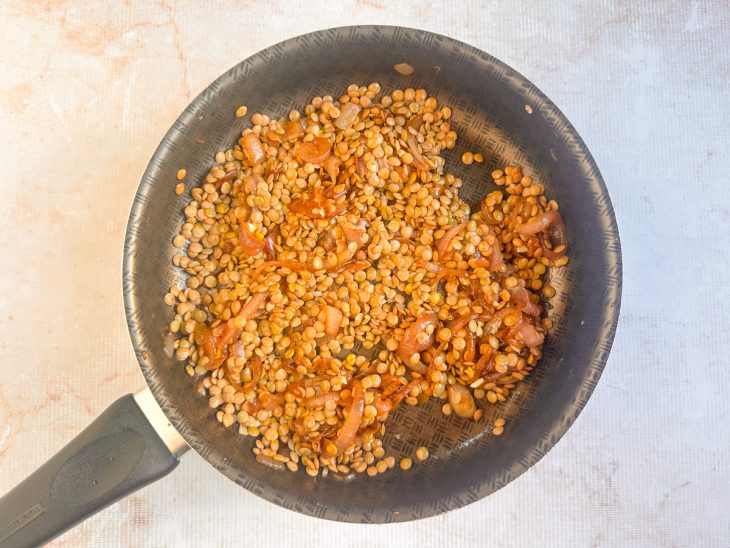 Lentilha crua sendo misturada ao refogado aromático.