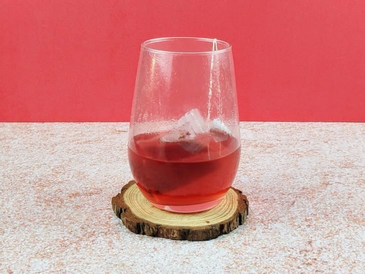 Sachê de chá infusionado em copo com água.