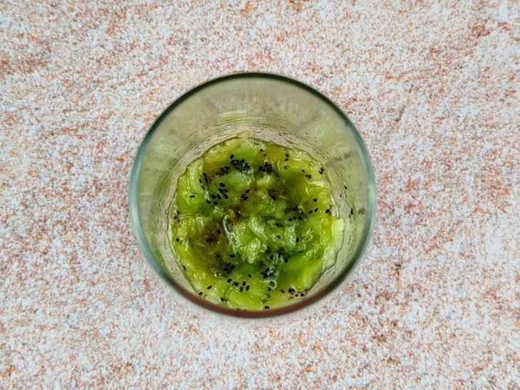 Kiwi levemente macerado em um copo de vidro.
