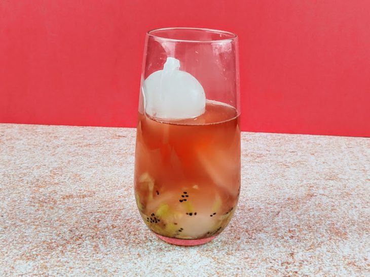 Chá de morango e gelo adicionados ao copo com kiwi.