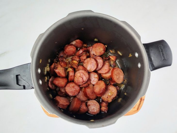 Bacon, calabresa, cebola e alho numa panela.