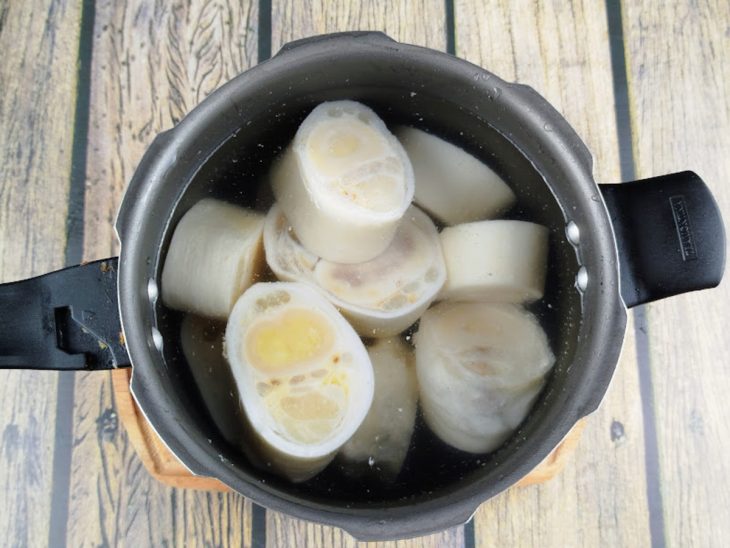 Mocotó cozinhando em uma panela de pressão com água e vinagre.