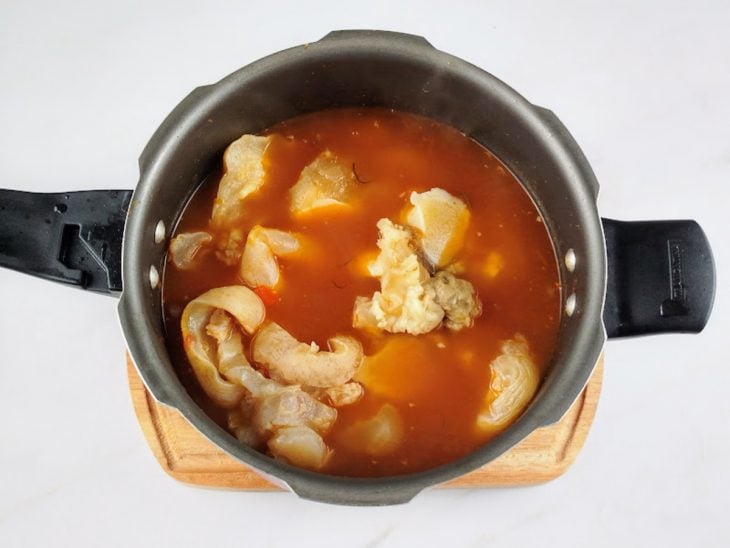 Tomate pelado, mocotó e água adicionados na panela.