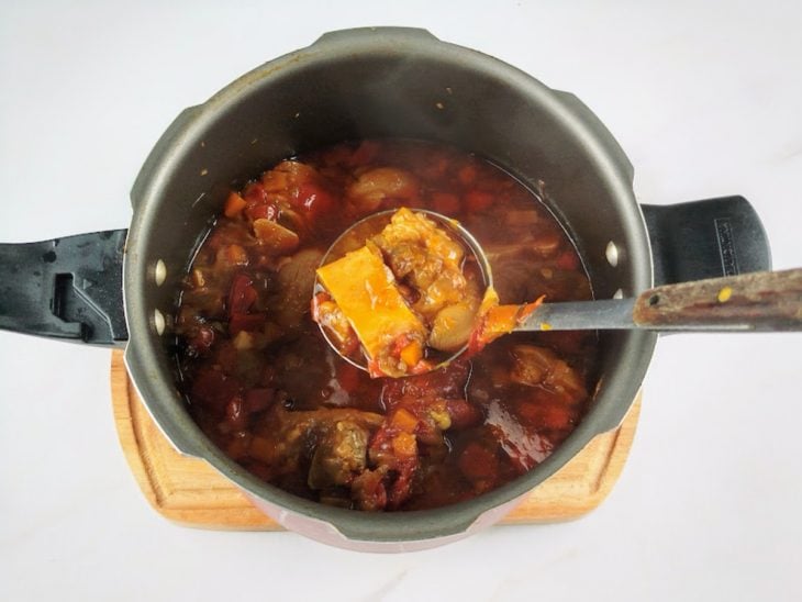 Porção de mocotó retirada da panela com uma concha.