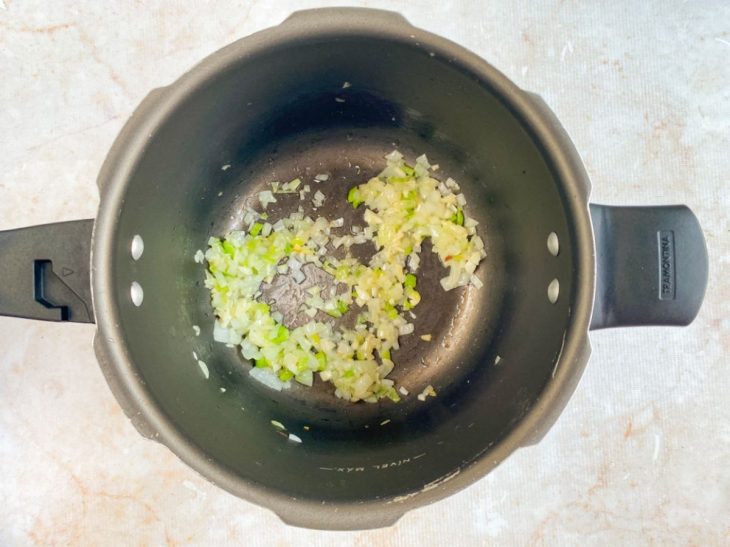 Na panela de pressão, alho e cebola sendo refogados.