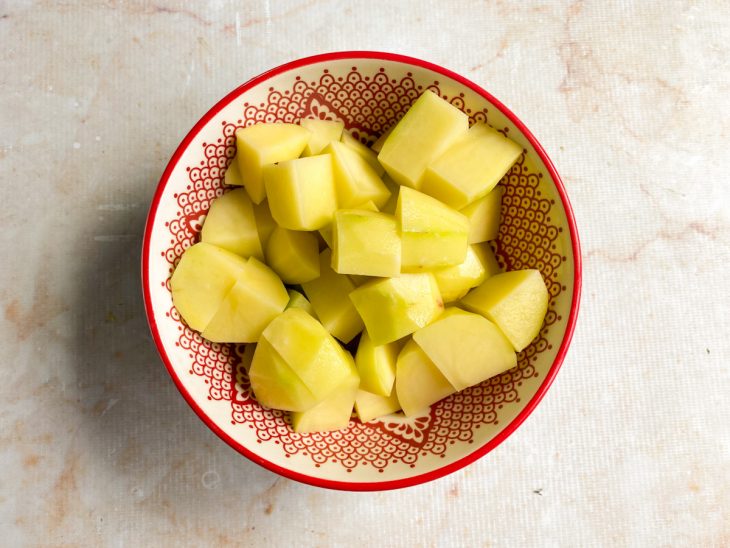Batatas numa tigelas, cortadas em cubos médios.