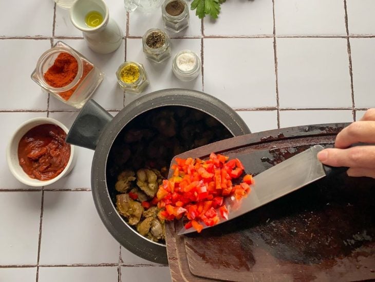 Uma panela de pressão contendo as moelas seladas e legumes.