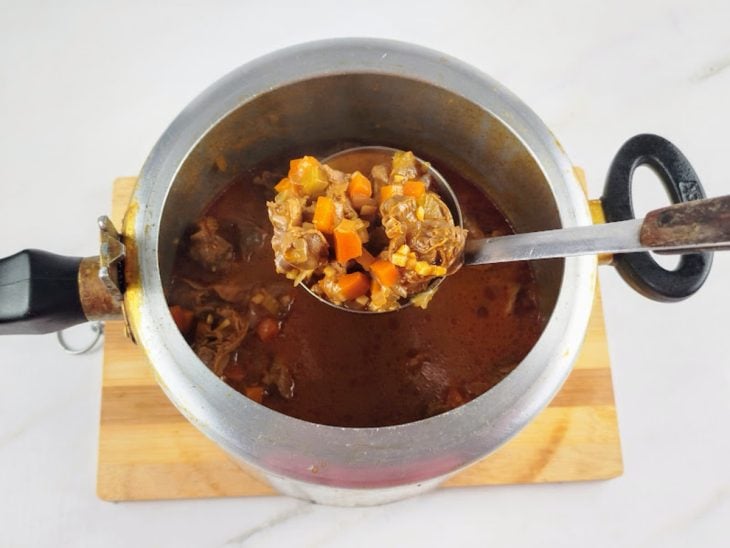 Panela de pressão aberta com a moela e molho ao ponto.
