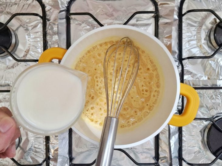 Leite sendo despejado na panela com o roux.