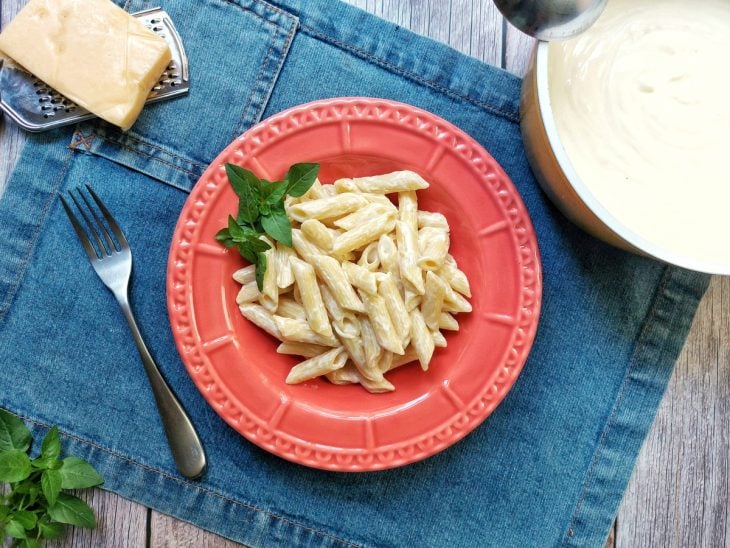 Um prato contendo macarrão com molho de branco.