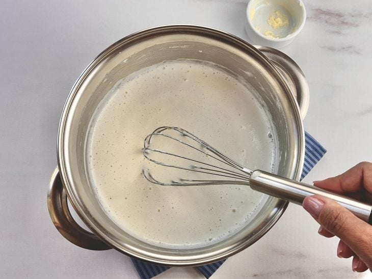 Uma panela com a mistura de leite, maizena, sal, noz-moscada e manteiga.