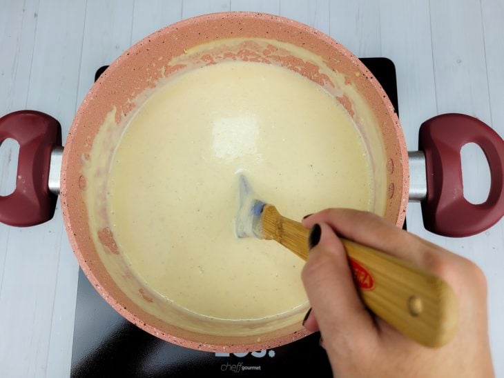 Uma panela com molho branco para lasanha em processo de cozimento.