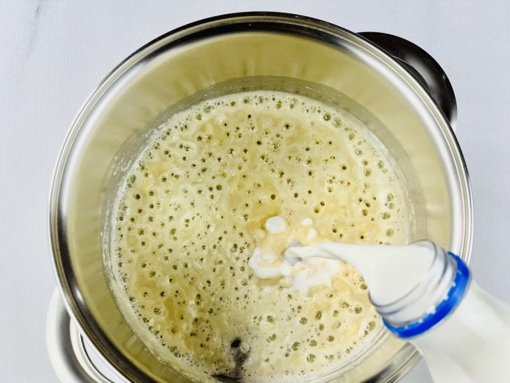 Na panela, leite sendo adicionado aos poucos.