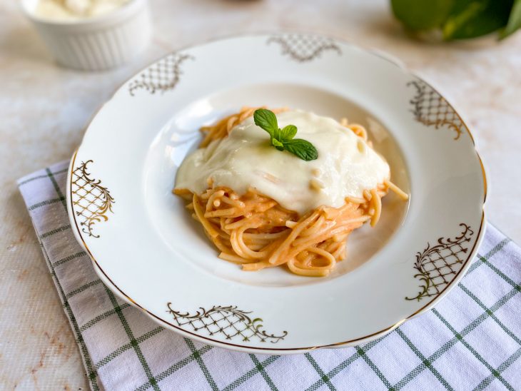 Molho branco pronto para consumo em um prato com macarrão.