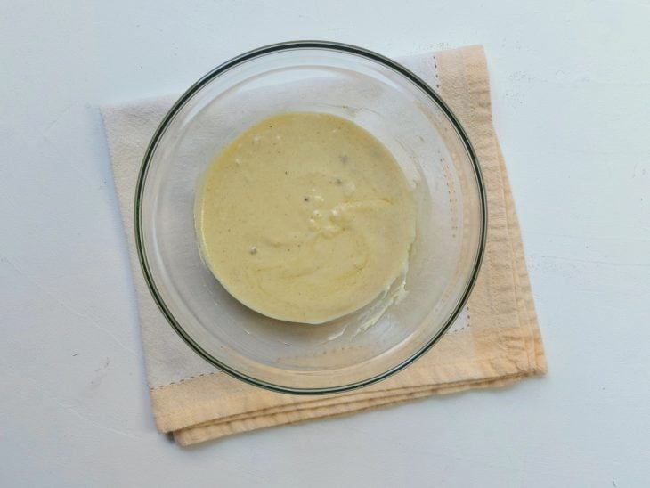 Um recipiente contendo a mistura de iogurte, molho inglês, mostarda, alho picado, alicce, sal, pimenta-do-reino e azeite.