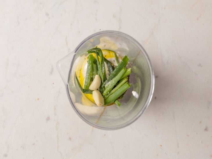 Creme de leite, alhos, cheiro-verde, sal e orégano em um liquidificador.
