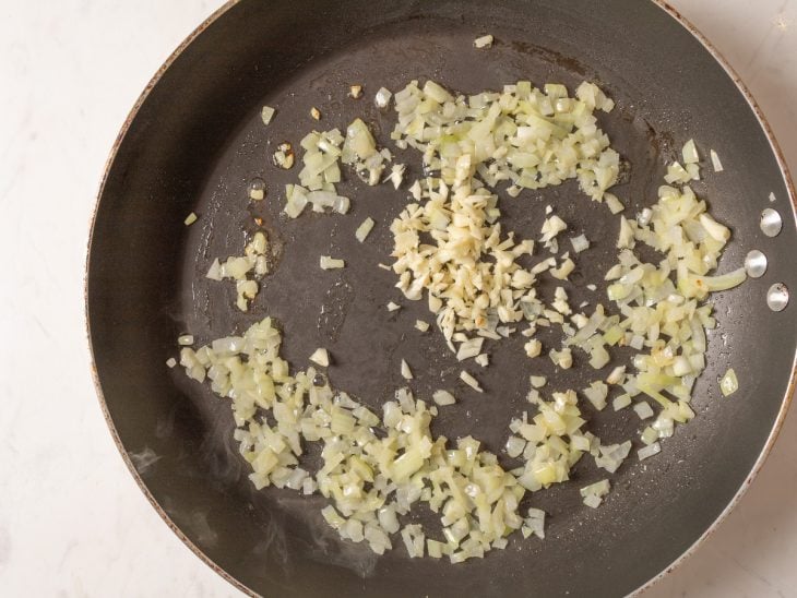 Uma frigideira com cebola, alho e manteiga.
