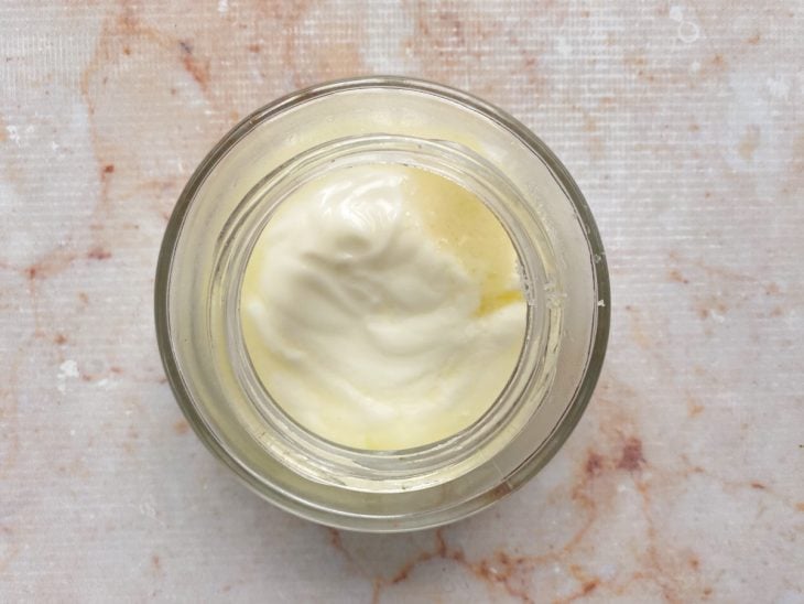 Iogurte natural, suco de limão e sal adicionados em um recipiente de vidro.