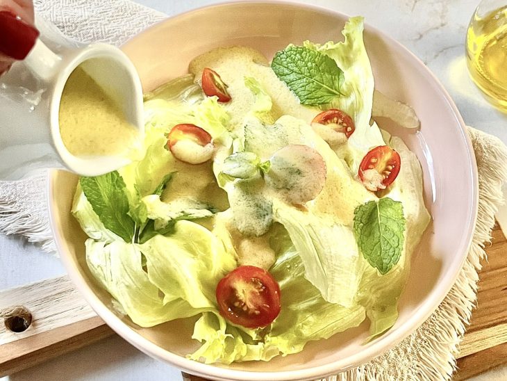 Molho de iogurte com mostarda dijon pronto para consumo, despejado sobre um bowl de salada.