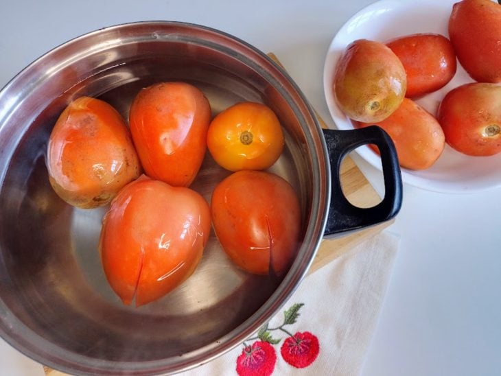 Uma panela com água quente e tomates.