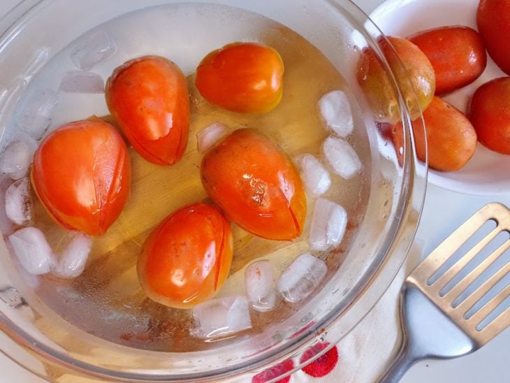 Um recipiente contendo água, gelo e tomates.